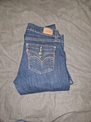 Vintage Levi’s jeans – omgjorda till bootcut, unik modell - PRIS KAN DISKUTERAS!LOW WAIST! Säljer ett par vintage Levi’s jeans i klassisk mörkblå denim. Jag har själv sytt om dem till bootcut, vilket ger dem en unik och trendig passform – perfekt för dig som gillar Y2K- och vintagevibbar.Jeansen har de ikoniska Levi’s-detaljerna på bakfickan och klassiska loggan. Denimkvaliteten är stadig och fortfarande i fint skick. Passa dem som har storlek M eller S I byxor! 🫶🏼💕