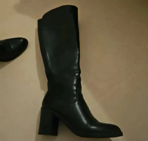 Svarta höga stövlar med klack använd 1 gång som nya - Snygga svarta stövlar med hög skaft och stabil blockklack. De har en spetsig tå och är tillverkade i slätt skinnmaterial som ger en stilren look. Perfekta för dig som vill ha ett statement-plagg till din outfit.