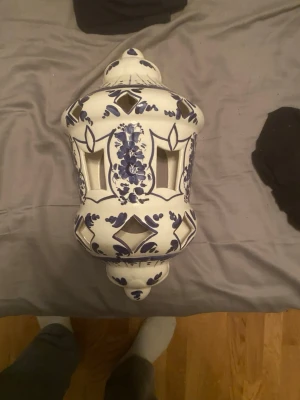 Fin inredning handgjord - Bilderna visar ingen väst utan en dekorativ keramiklykta i vitt och blått med blommönster och utskurna detaljer. Ingen information om väst kan ges.