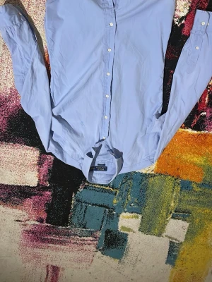 Ljusblå skjorta från Polo Ralph Lauren - Klassisk ljusblå skjorta från Polo Ralph Lauren med broderad logga på bröstet. Skjortan har lång ärm, knappar framtill och en snygg krage. Perfekt för dig som gillar stilrena och tidlösa plagg.