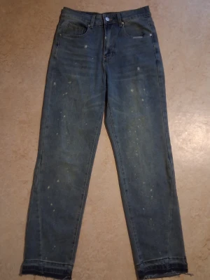 Blå raka jeans från Fashion Jeans XXS - Säljer ett par blå jeans från Fashion Jeans i storlek XXS. Jeansen har raka ben, hög midja och råa kanter nertill. Materialet är en mix av bomull, polyester, viskos och elastan. Coola färgstänk ger en unik vintagekänsla.