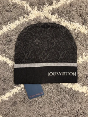 Svart L mössa - Mössan har broderad mönsterl och är tillverkad i mjukt stickat material. Perfekt accessoar för dig som vill ha en lyxig och stilren look.