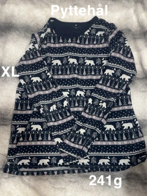 Mörkblå långärmad pyjamaströja med björnmönster - Långärmad pyjamaströja i mörkblått med vitt och grått mönster av björnar, granar och snöflingor. Perfekt för vintriga dagar med sitt mysiga print och avslappnade passform. Rund halsringning och mjukt material.🌸Litet hål. Storlek XL