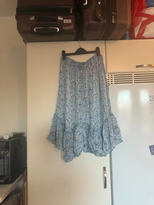 Blommig blå volangkjol Odd Molly - Supersöt långkjol i ljusblått med blommigt mönster i blå och beige toner. Kjolen har bred resår i midjan och volang nedtill som ger en flowy och chill vibe. Perfekt för dig som gillar boho-stil och vill ha något bekvämt och snyggt. Från märket Odd Molly. Storlek 2 som enligt deras storleksguide motsvarar en M. Mycket fint skick, jag hittar inga synliga anmärkningar eller defekter. 