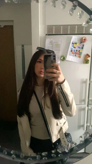 MANGO Beige skinnjacka med bälte och dragkedjor - Säljer en beige skinnjacka med coola detaljer som bälte i midjan och flera dragkedjor. Jackan har en croppad passform, klassisk krage och långa ärmar. Perfekt för dig som vill ha en edgy och stilren look.