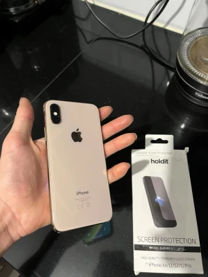 iPhone XS 64GB - Snygg iPhone XS i guld, Mobilen är i fint skick utan synliga repor eller skador. Levereras med skärmskydd från Holdit för extra skydd. Perfekt för dig som vill ha en kraftfull och stilren iPhone. inga skador repor eller sprickor ! Helt ny telefon Skärmen är helt nytt och batteri tiden håller hela dagen! Högtalaren är väldigt bra inga defekter! batteriet nyligen bytt (inte äkta) Skärmskydd följer med