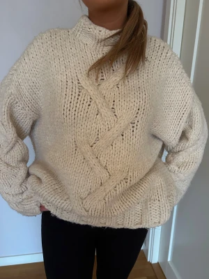 Vit stickad med flätmönster - Vit stickad tröja med snyggt flätmönster framtill och på ärmarna. Tröjan har en lite högre krage och oversize passform. 💕💕