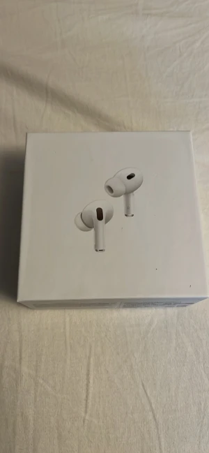 AirPods Pro (2nd generation) - Säljer ett par AirPods Pro (2nd generation) från Apple, modell A2698/A2699/A2700. Komplett med originalförpackning, laddningskabel och extra öronkuddar. Produkten ser ut att vara i nyskick utan synligt slitage eller defekter. Perfekt för dig som vill ha aktiv brusreducering och hög ljudkvalitet.