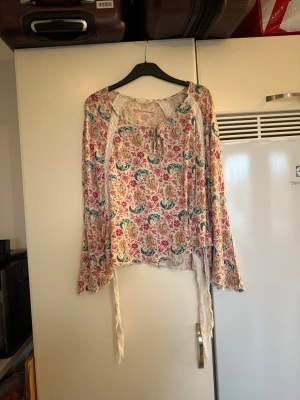 Odd molly blus  - Säljer en superfin poncho blus i en superfin cremevit färg men ett superfint mönster i grön/blå, rosa, ljusblå och orange. Från märket Odd Molly. Storlek 2 som enligt deras storleksguide motsvarar en M. Mycket fint skick, jag hittar inga synliga anmärkningar eller defekter. 