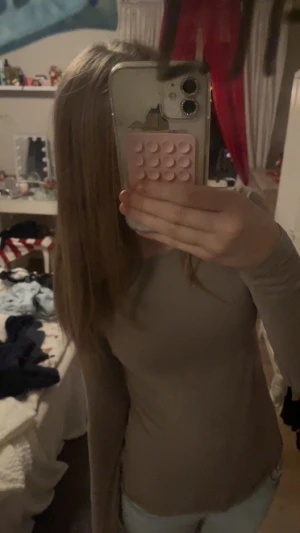 Beige långärmad topp i stretch - Säljer en enkel och stilren beige långärmad topp i stretchigt material. Modellen är figurnära och har rund halsringning. Perfekt att matcha med jeans eller kjol för en clean look. storleken är XS men passar även som en S.