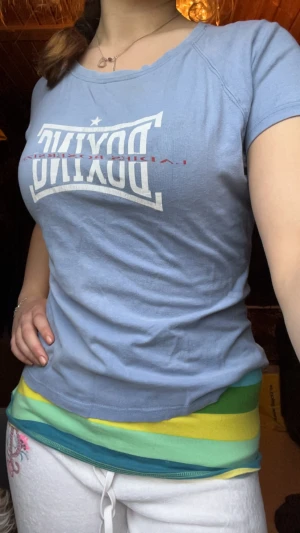 Ljusblå BOXING t-shirt från Melly - Ljusblå t-shirt från Melly med trycket 'BOXING' i vitt framtill. Klassisk rund halsringning och korta ärmar. Perfekt för dig som gillar sportiga vibes och enkel stil.