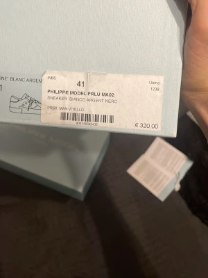 Philippe Model sneakers vit/silver 41 - Säljer ett par Philippe Model PRLU MA02 sneakers i vitt och silver med svarta detaljer. Skorna har snörning, rund tå och är tillverkade i skinn. Klassisk och trendig design med metallic-detaljer och logga på sidan. Perfekta för dig som gillar exklusiva sneakers med unik look. Priset kan diskuteras vid en snabb affär använda några gånger och köpte dom av en vän för 2500kr hör av er om ni har några funderingar eller något