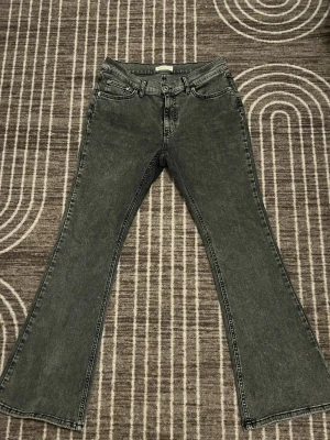 Svarta bootcut jeans med hög midja - Snygga svarta jeans med bootcut passform Jeansen har klassisk femficksdesign, dragkedja och knapp framtill. Materialet är jeans med en tvättad look som ger en cool vibe. Perfekta för dig som gillar retrostil och vill sticka ut.