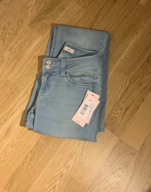 Ljusblå bootcut jeans från Nelly - jätte snygga jeans som är helt ny med pris lapp 💗 jag råkade köpa ett par för stora och hann inte med returrättett men jeansen har en rosa broderad zigzag på bakfickorna och har en låg midja med bootcut-ben. materialen är väldigt najs och den är gjorda i bomulls material, den ordinarie prisen är 699 kr 😔🫶