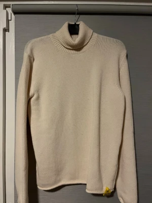 Vit tröja från John Sterner - Säljer en stilren vit polotröja från John Sterner i storlek M. Tröjan är stickad i mjuk ull och har en klassisk ribbad polokrage samt långärmad passform. En gul detalj med JS 0699 sitter vid nederkanten som markerar fåret som användes. Perfekt för kyliga dagar! Hör av er vid intresse 🤩