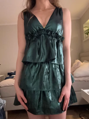 Glittrig grön volangklänning med v-ringning - Säljer en jättefin grön glittrig nyårsklänning från Zara i storlek xs. Använd en gång.☺️