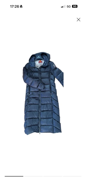 Svart lång dunjacka Parajumpers S - Säljer en svart lång dunjacka från Parajumpers, modell Sheen. Jackan har huva, hel dragkedja och quiltad design. Insidan är ljusbeige och jackan har två sidofickor med dragkedja. Perfekt för kalla dagar och har en clean, stilren look.