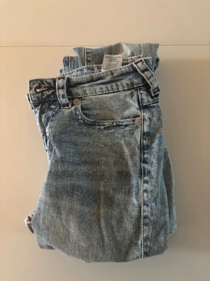 True Religion BECCA bootcut jeans - Snygga ljusblå jeans från True Religion, modell BECCA Mid Rise Bootcut. Bootcut passform med slitna detaljer och röd broderad logga på bakfickorna 💗