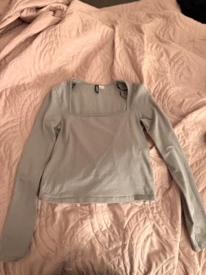 Grå långärmad topp  - Säljer en grå långärmad topp från H&M med en snygg fyrkantig halsringning. Toppen är i mjuk bomull.