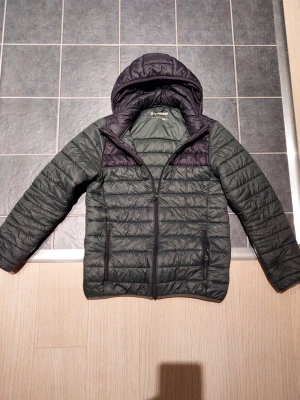 Mörkgrön pufferjacka från Everest - Säljer en mörkgrön pufferjacka från Everest med svarta detaljer och huva. 