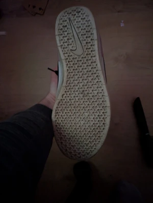 Nike SB sneakers i svart och vitt - Nike SB sneakers med svart swoosh, vit ovandel och rosa mockadetalj vid hälen. Skon har snörning och platt sula med mönstrad undersida. Materialmix av skinn och mocka, perfekt för dig som gillar streetstyle och skate.