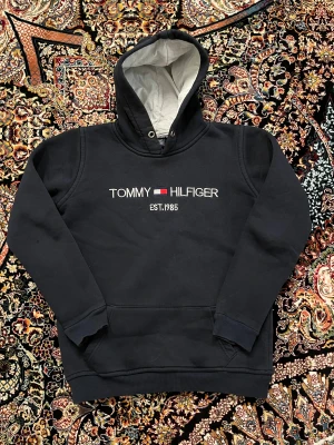Tommy hilfiger hoodie  - Säljer min Tommy hilfiger hoodie för bra pris och bra skick, säljer på grund av att den är liten för mig. Priset kan diskuteras, vill bli av med den ! Den är typ mörkblå, den kanske ser ut svart men är mörkblå. 