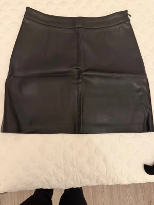Svart skinnkjol från Gina Tricot - Säljer en svart kort skinnkjol från Gina Tricot i storlek 36. Sitter fint på kroppen. Använd ett fåtal gånger. Säljs pågrund av flytt städ
