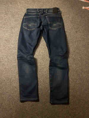 Replay Hyperflex mörkblå jeans - Säljer ett par Replay Hyperflex jeans i mörkblå färg med snygga kontrastsömmar och klassiska bakfickor med broderad detalj. Modellen har slim passform och är tillverkad i super stretchigt jeansmaterial som ger grym komfort. Perfekt för dig som gillar stilrena och bekväma jeans. NYPRIS 1800kr! 
