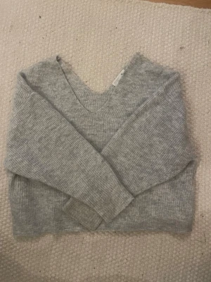 Stickad tröja - En grå stickad tjocktröja med V- urringning 