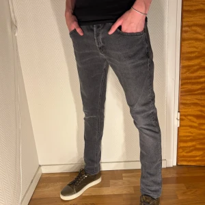 Dondup jeans - Säljer ett par grå jeans från Dondup med slim fit passform och klassisk femficksdesign. Jeansen har svarta detaljer på bakfickorna och är tillverkade i mjukt jeansmaterial med stretch. Perfekta för dig som gillar en smal siluett och stilren look.