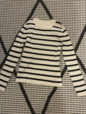 Randig ribbad tröja från Zara - Säljer en vit och svart långärmad tröja från Zara i storlek 152. Tröjan har ett ribbat tyg och klassiska horisontella ränder. Rund halsringning och mjukt material som är skönt mot huden. Perfekt för dig som gillar enkel och stilren design.