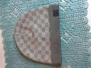 Grå rutig mössa från Louis Vuitton - Snygg grå mössa från Louis Vuitton med rutigt mönster och uppvikt kant. Mössan har en diskret logotyp på kanten och är tillverkad i mjukt stickat material som känns skönt mot huvudet. Perfekt för dig som vill ha en stilren accessoar med lyxig touch.