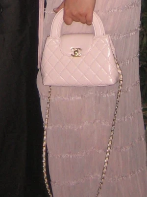 Ljusrosa quiltad handväska  - Säljer en ljusrosa handväska med klassiskt quiltat mönster och guldfärgad kedja. Väskan har ett elegant handtag och ikonisk logga framtill. Perfekt storlek för det viktigaste och ger en lyxig vibe till din outfit.