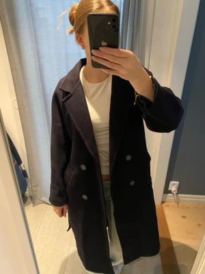 Kappa - Säljer en  mörkblå kappa i mycket fint skick. Kappan är lång och har raka ärmar samt två fickor. (Jag är 170cm lång) 