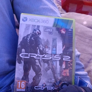 Crysis 2 Xbox 360 - Crysis 2 till Xbox 360, komplett med originalfodral och skiva. Fodralet och omslaget är i gott skick, och skivan ser ut att vara fri från större repor. Ett actionfyllt FPS-spel med både kampanj och multiplayer. Perfekt för samlare eller spelentusiaster.