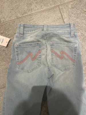 Blåa bootcut jeans från Nelly, stl 38 - Pris går att diskuteras💕Snygga ljusblå bootcut jeans från Nelly med låg midja. Jeansen har coola rosa detaljer på bakfickorna och klassisk femficksdesign. Tillverkade i mjukt jeansmaterial och perfekta för en trendig look.