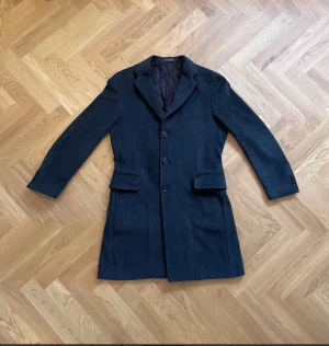 Oscar Jacobson mörkgrå kashmir / ull rock - Bra skick | Herrkläder | 46 | Oscar Jacobson  Elegant borstad mörkgrå Oscar Jacobson rock i storlek 46. Rocken har en klassisk design med tre knappar framtill och två fickor. Perfekt för både vardag och uppklädda tillfällen. Rocken är i ett mycket fint skick.  Modell: Synder Coat Material: Cashmere, Wool & Polyamide  Skriv vid frågor!  Fraktar samma dag. 