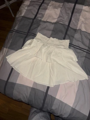 Vit volangkjol med smock - Supersöt vit kortkjol med bred smock i midjan och dubbla volanger.