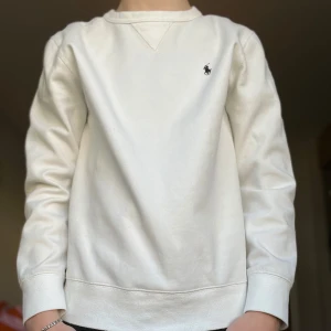 Vit tröja från Polo Ralph Lauren - Säljer en stilren vit tröja från Polo Ralph Lauren med deras ikoniska logga broderad på bröstet. Tröjan har långa ärmar och en klassisk rund halsringning. Perfekt för en avslappnad och snygg look. Storlek s och passar dig runt 180