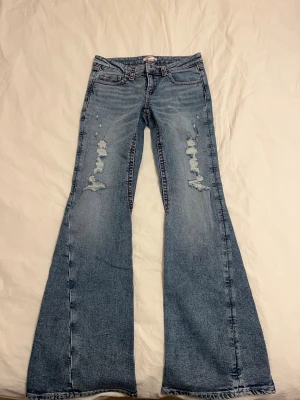 Bootcut jeans med rosa sömmar Gina Tricot - Bootcut jeans från Gina Young storlek 164 i ljusblå tvätt med slitna detaljer framtill och rosa sömmar. Baksidan har fickor med broderade mönster. Använda endast 1 gång för dem är lite långa på mig som är 158cm 💕