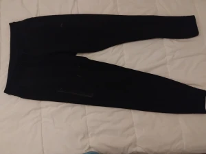 Svarta mjukisbyxor med snörning - Svarta mjukisbyxor med smal passform och snörning i midjan. Byxorna har dragkedja på fickan och är gjorda i mjukt material som känns skönt mot huden. Perfekta för chill eller träning. Enkla att matcha med hoodies eller t-shirts.