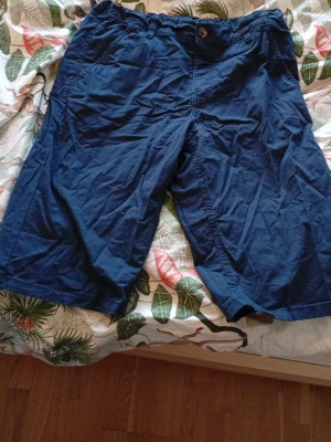 Marinblå shorts från Kappahl - Säljer ett par marinblå shorts från Kappahl i storlek 170. De har normal passform, klassisk knapp och dragkedja framtill samt fickor både fram och bak. Materialet är mjuk bomull, perfekt för varma dagar. Snygga och enkla att matcha med t-shirt eller hoodie. Dom är i fint skick men måste strykas. Pris kan sänkas vid en villig affär