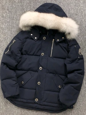 Moose Knuckles  - Säljer en mörkblå dunjacka från Moose Knuckles med fluffig ljus päls på huvan. Jackan har flera snygga detaljer som silverfärgade knappar, dragkedjor och logotyp på ärmen. Broderad insida med hockeymotiv. Perfekt för kalla dagar.