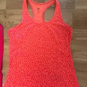  träningslinne i neonrosa - Säljer snygg träningslinnen i neonrosa. H&M har ett helöverdraget leopardmönster. Den har  har brottarrygg och är tillverkade i lätt, stretchigt material som andas.