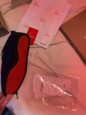 Christian Louboutin svarta sneakers strl 45 - Säljer ett par svarta sneakers från Christian Louboutin i storlek 45. Skorna har en ikonisk röd sula, rund tå och är tillverkade i mocka med snörning framtill. Insidan är beige och de kommer med originalkartong och dustbag. Perfekt för dig som gillar exklusiva detaljer.