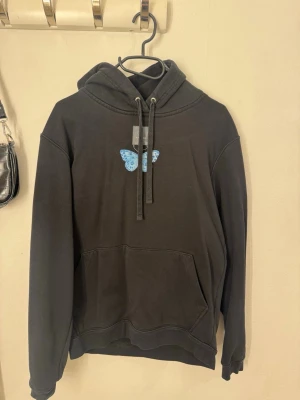 The cool elephant  - Svart hoodie från the cool elephant. Den är väl använd men utan några defekter förutom att materialet inte är lika ”mjukt”. Annars är den väldigt fin både framtill men speciellt baktill med det fina fjäril trycket. 