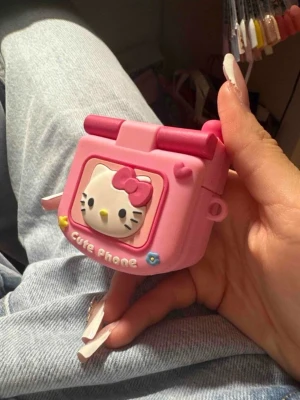 Hello Kitty AirPods-fodral - Sött AirPods-fodral i form av en rosa retro mobil med Hello Kitty-design. Fodralet har spegel på insidan och plats för AirPods, passar perfekt för att skydda och förvara dina hörlurar. Skicket ser ut att vara mycket bra utan synligt slitage. För AirPods 3, pro.3 och 4 