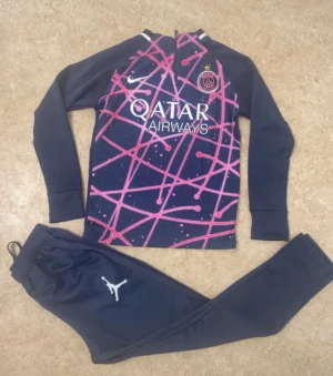 Inga skor på bilderna - Bilderna visar ett träningsset med långärmad tröja och byxor från PSG x Jordan, men inga skor finns med.