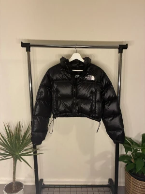 Croppad pufferjacka - Svart croppad dunjacka från The North Face i fint skick. Varm, lätt och justerbar i nederkant. Nypris köpt för 300 euro