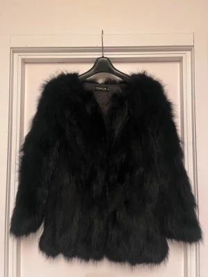 Svart pälsjacka från Tonfur - Säljer en svart pälsjacka från Tonfur med fluffig och lyxig look. Jackan har lång ärm och en rak, loose passform som ger en cool vibe. Perfekt för dig som vill sticka ut med en statement piece i garderoben. Jackan är helsvart och har en mjuk pälsstruktur. Storlek M. Jättebra skick! Ligger ute på flera säljsidor. Först till kvarn. 
